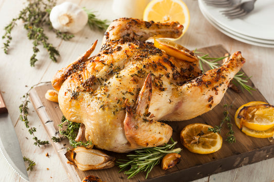 A whole roast chicken, garnished with lemon and rosemary